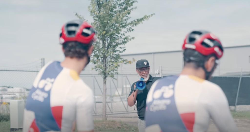 Raye Ackerman with a megaphone speaking to two racers at the York Durham Crit Series
